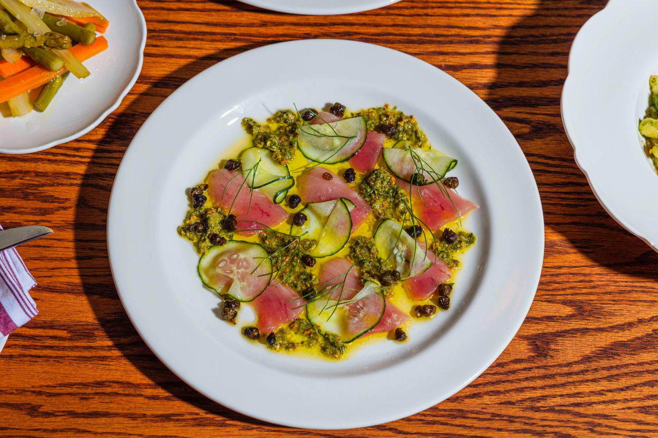 Silky albacore tuna crudo with fresh cucumbers is punched up with salty minced Castelvetrano olives, fried capers and pistachios