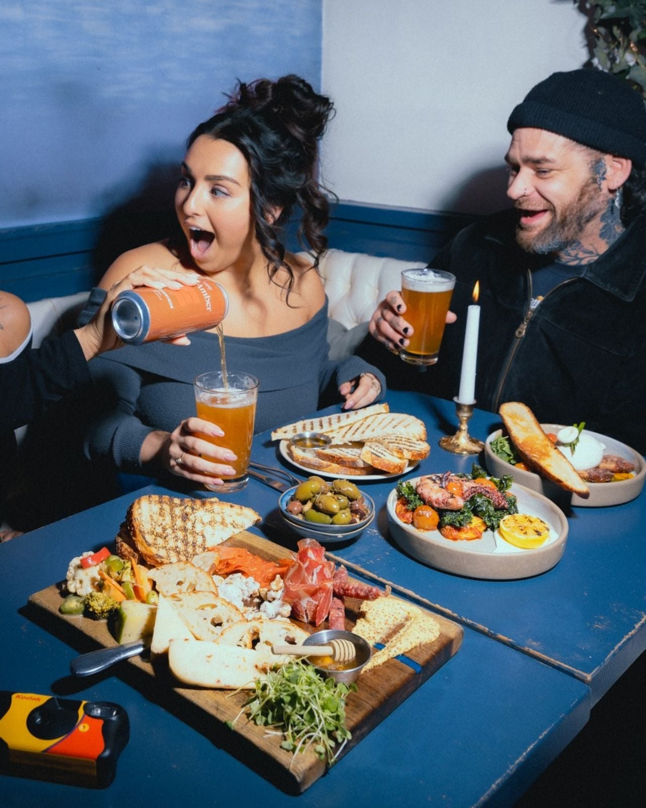 People sit around tables of food with pints of beer at Everyside, a restaurant and brewery in Toronto