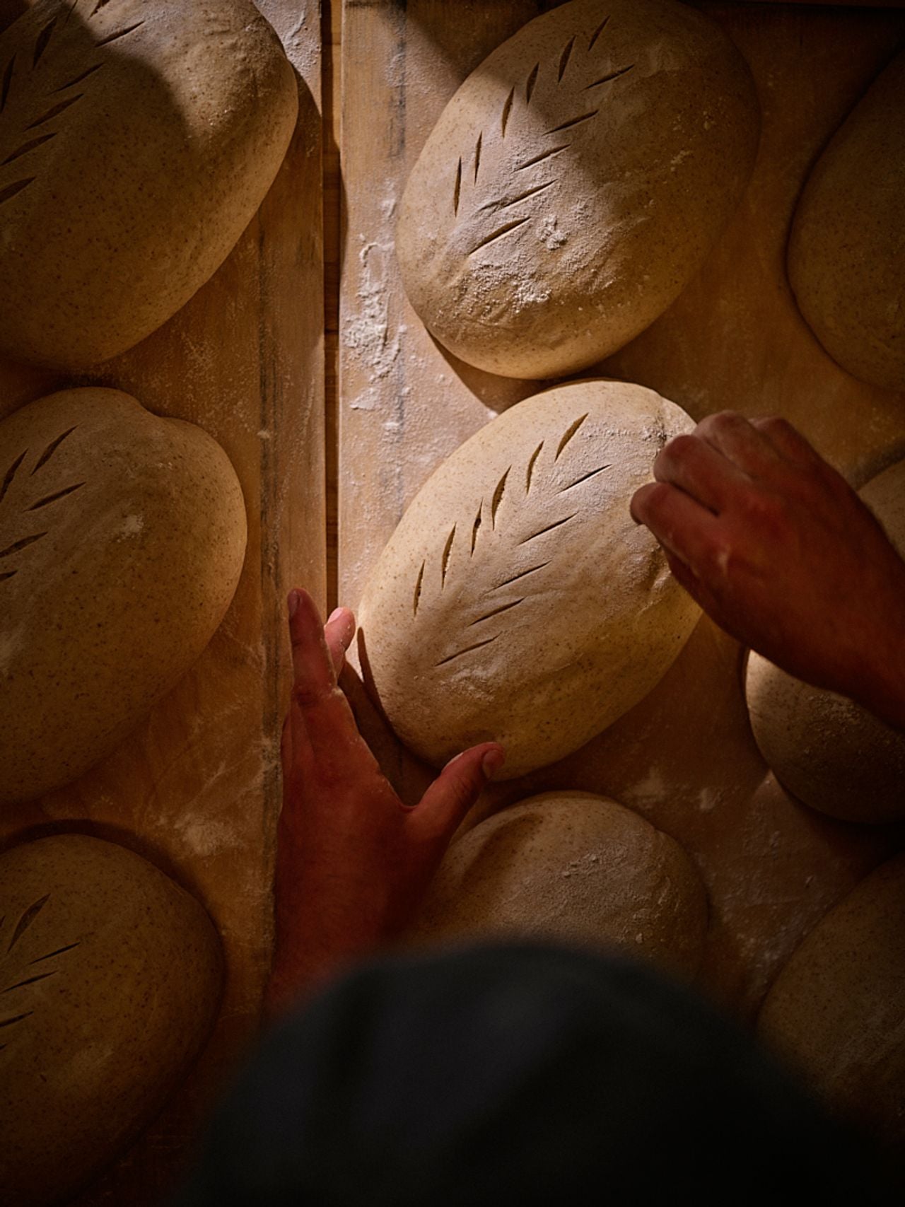 A bakery scores a loaf of unbaked sourdough bread