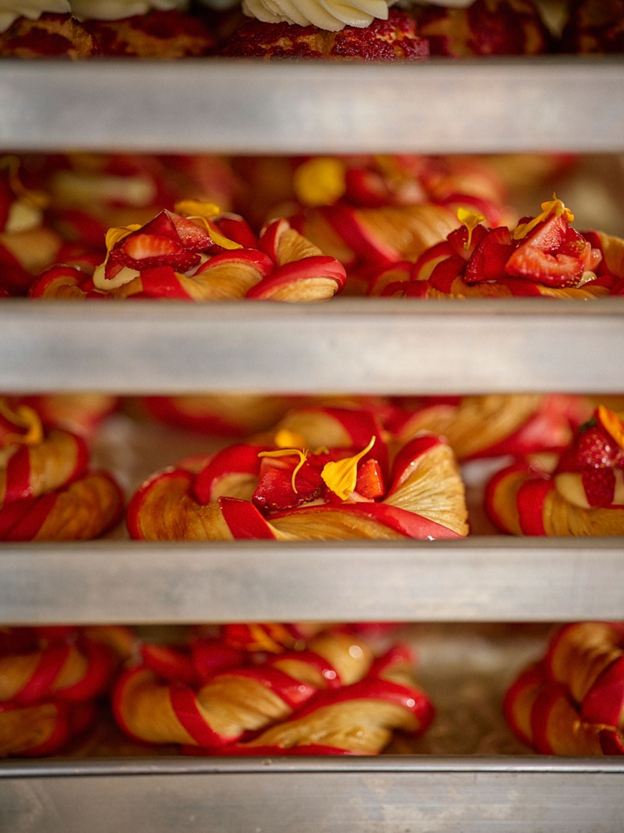 A baker's rack filled with strawberry-topped pastries