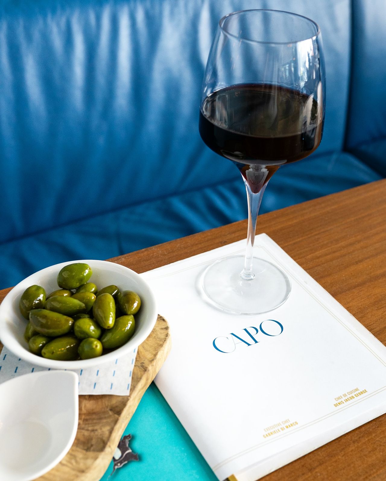A bowl of olives and a glass of red wine at Capocaccia in Toronto