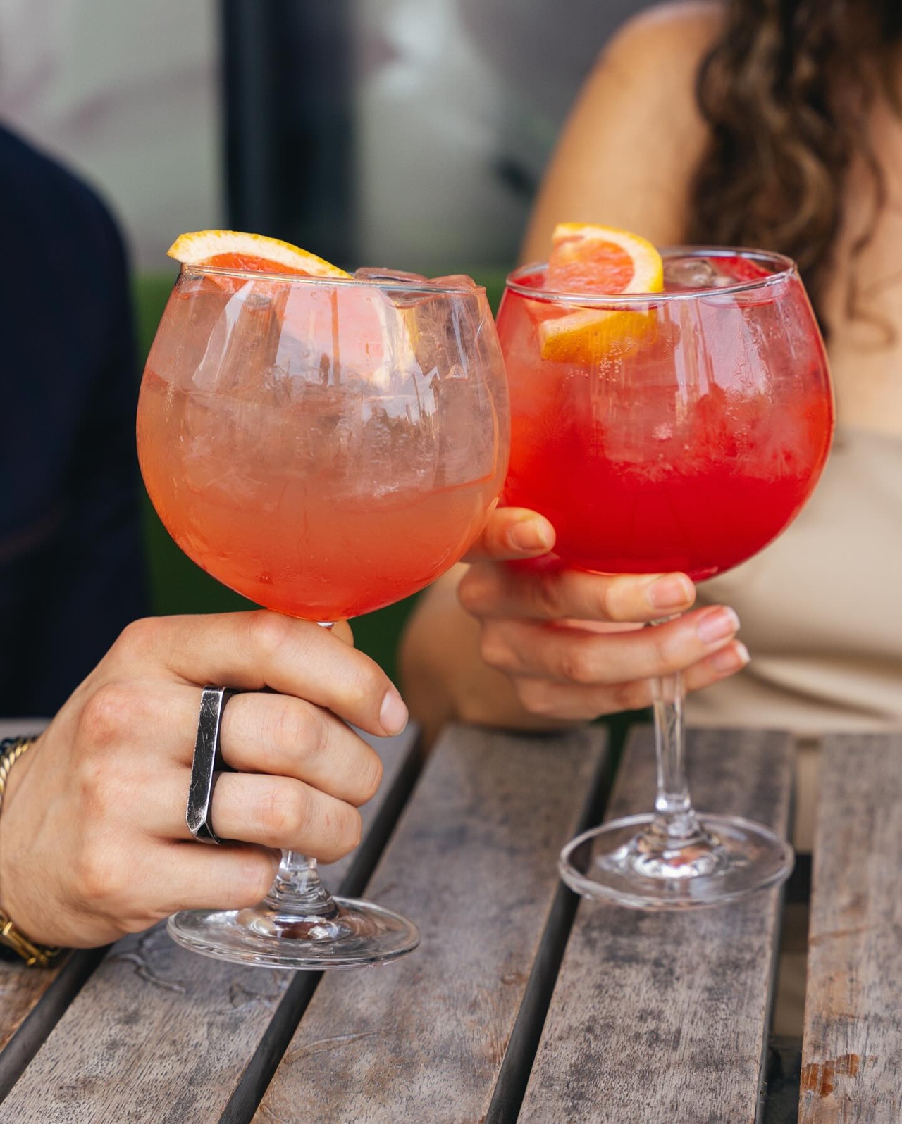 People clink glasses of Aperol spritzes together during Figo's aperitivo hour