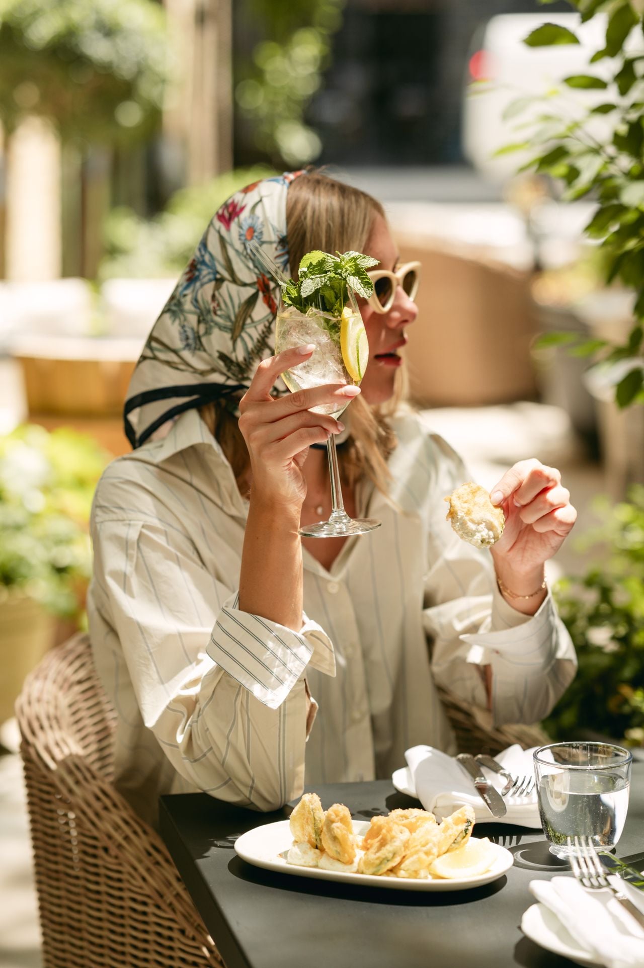 A woman holds a drink in her hand on Florin's patio during aperitivo hour