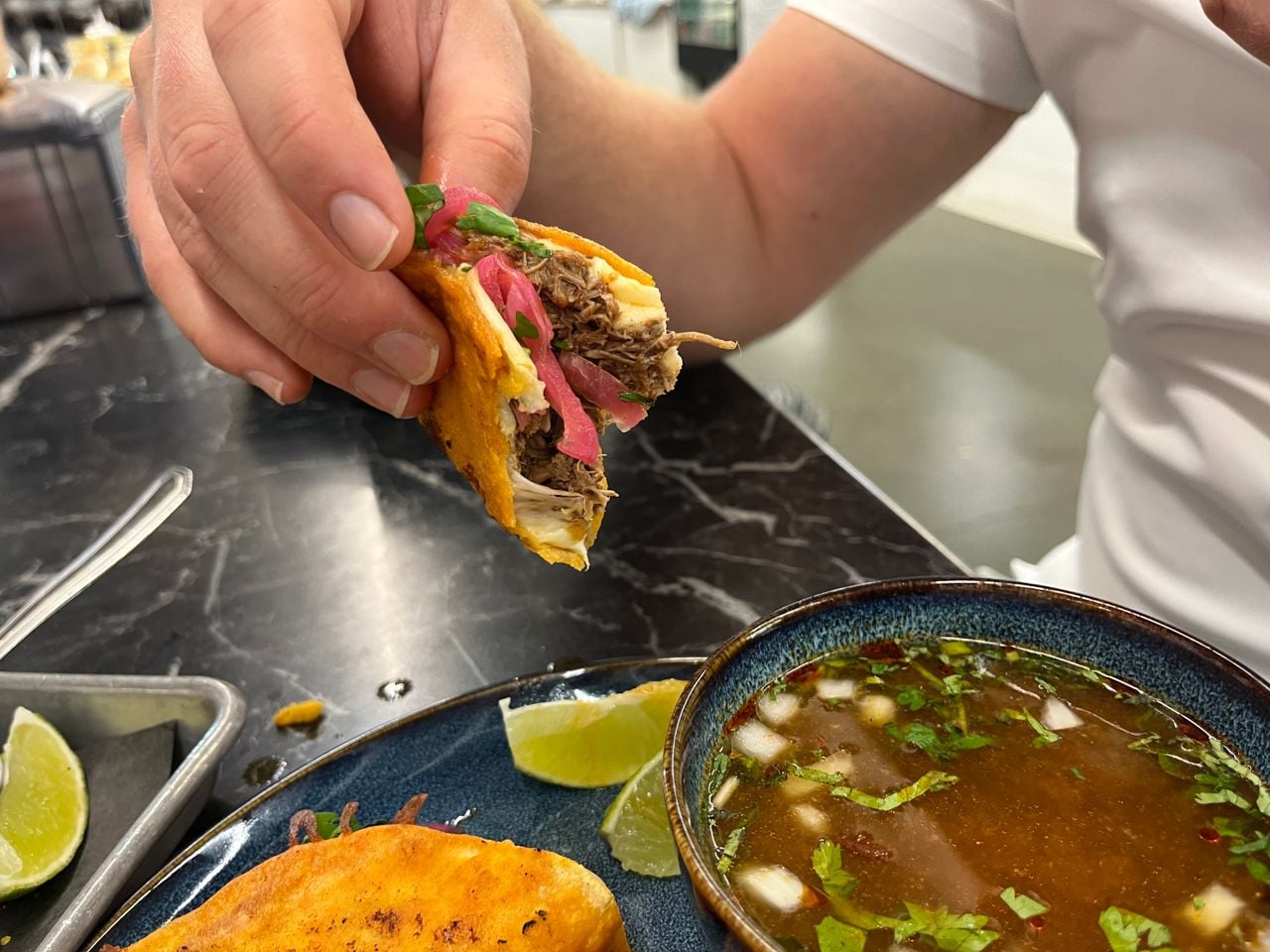 A closeup of a birria taco with a bite out of it