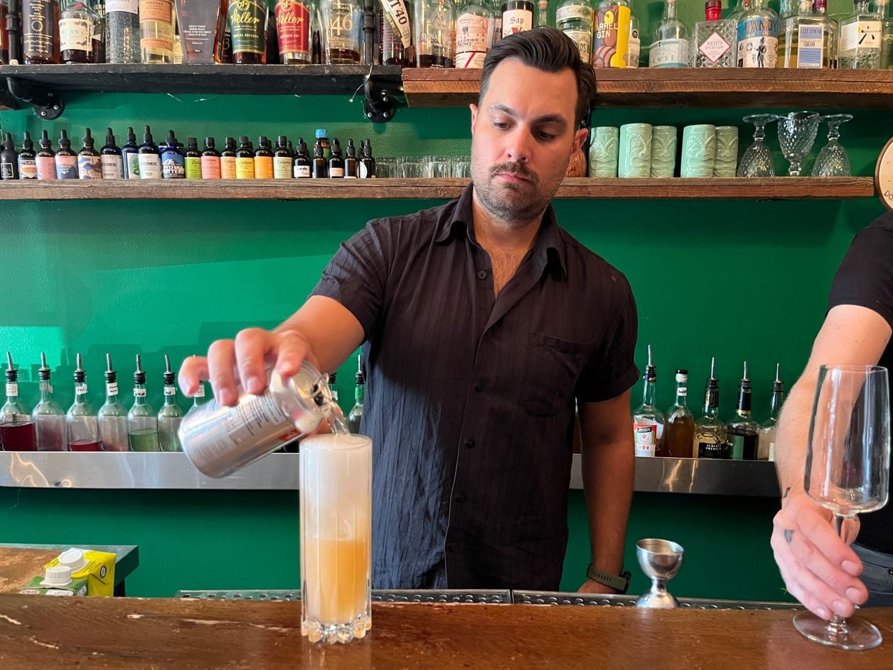 The bartender at Bar Sazerac tops up a cocktail with soda water