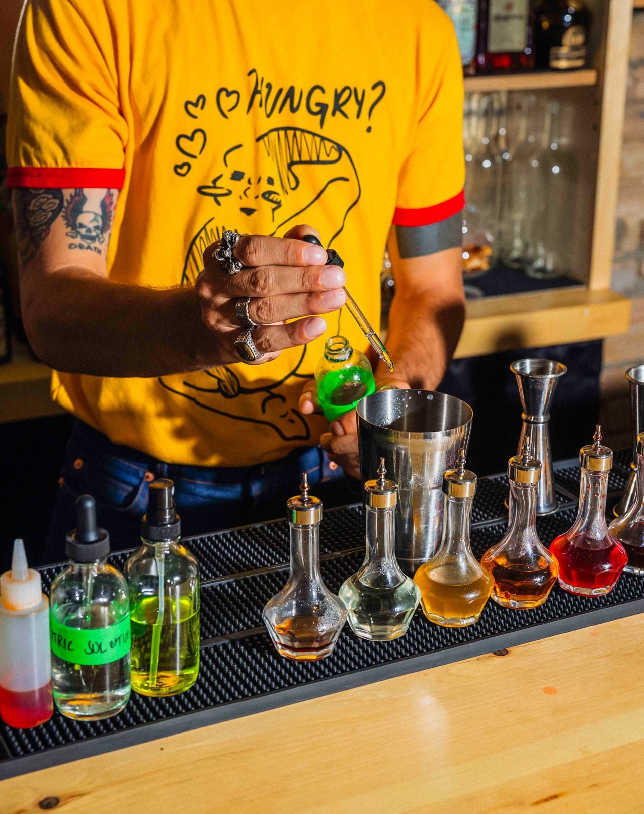 The bartender at Bar Mini adds a tincture to a cocktail shaker using an eye dropper
