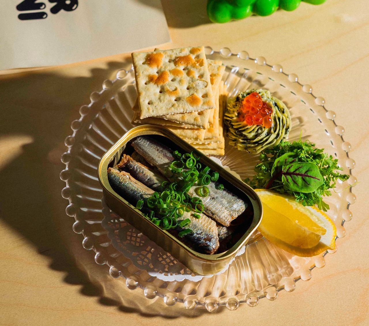 These chive-topped tinned sardines are paired with saltines, whipped seaweed butter and salmon roe, more herbs and lemon