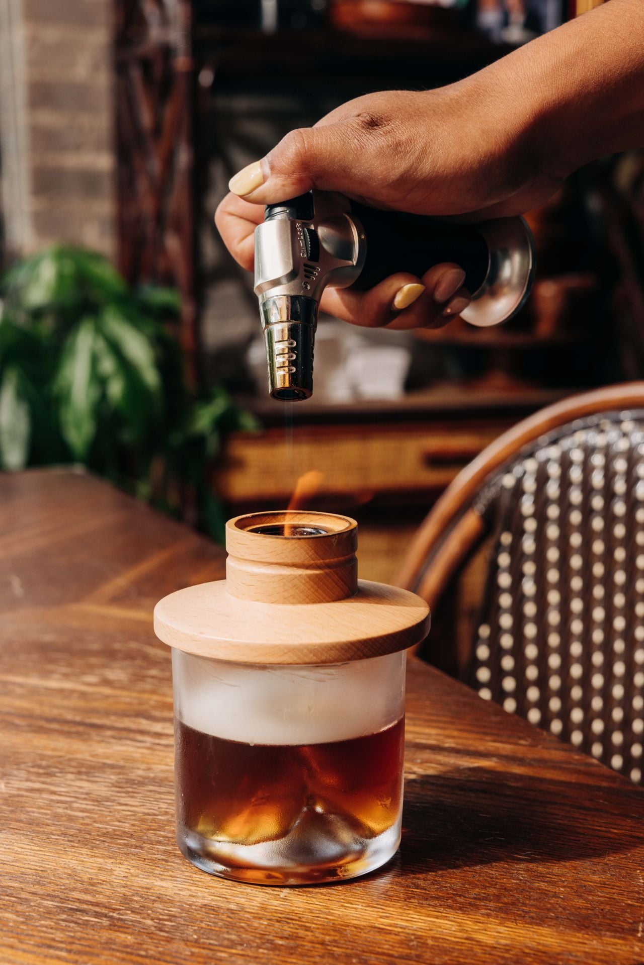A person uses a lighter to light a smoked cocktail