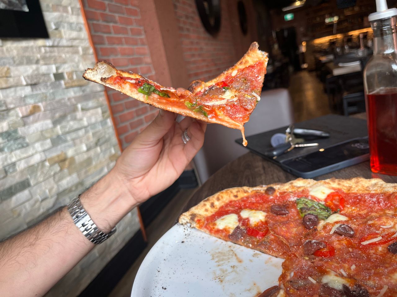 A person holds up a slice of pizza