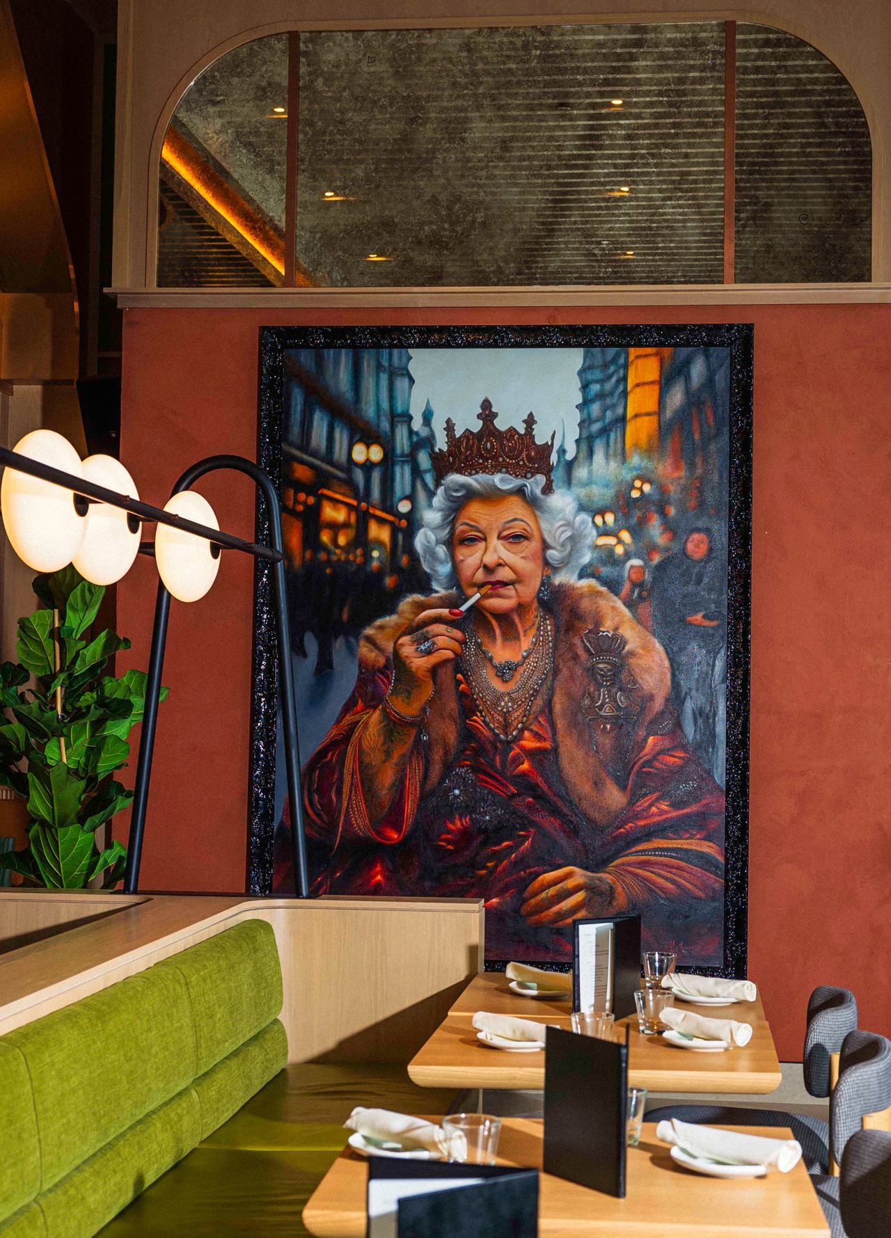 A painting of the queen smoking a cigarette hangs on a wall inside Queens Harbour