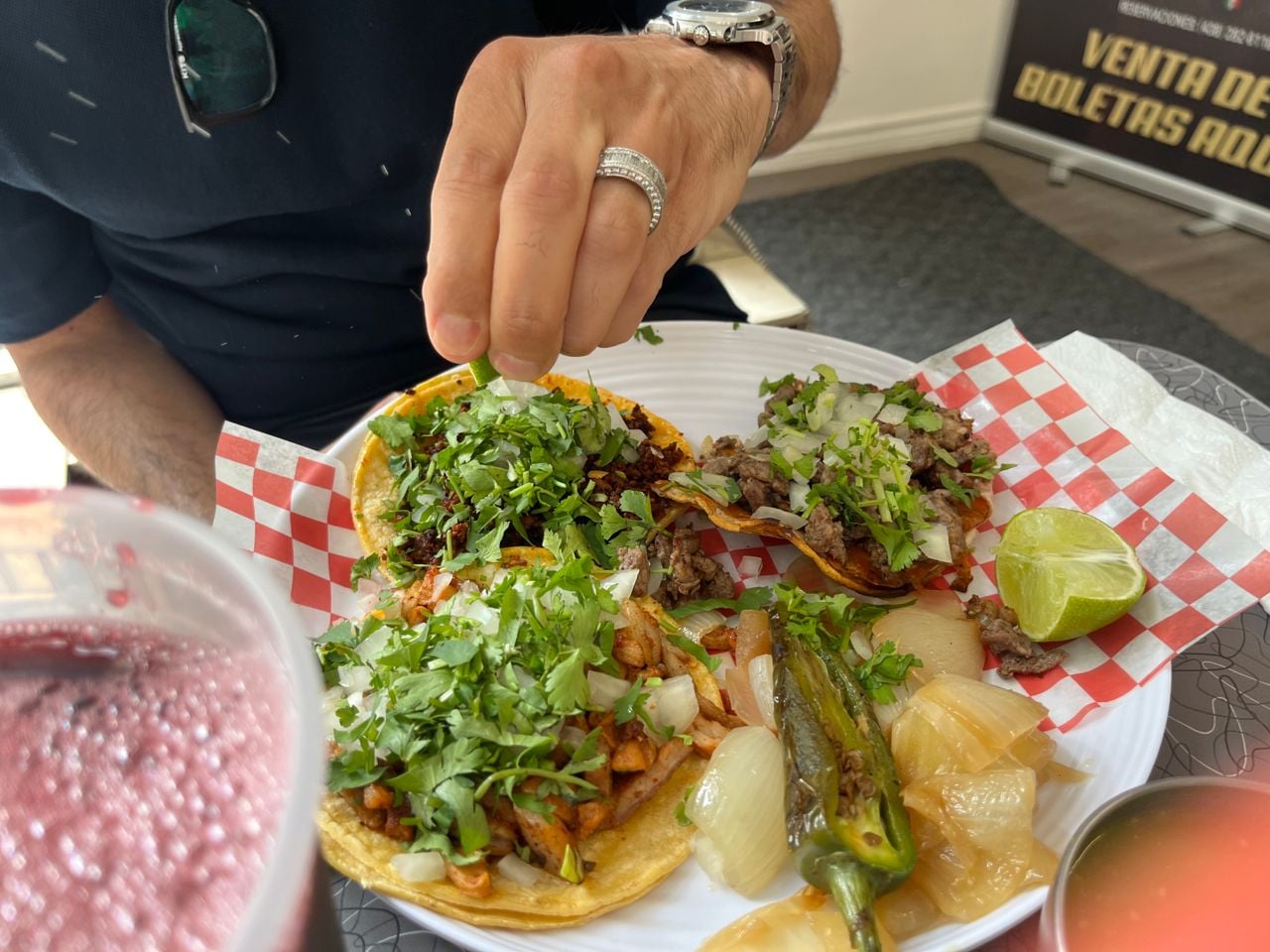 A person squeezes lime juice over a plate of tacos
