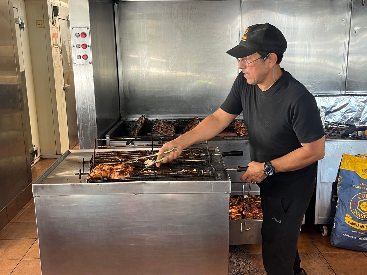 A man uses tongs to take chicken off a grill