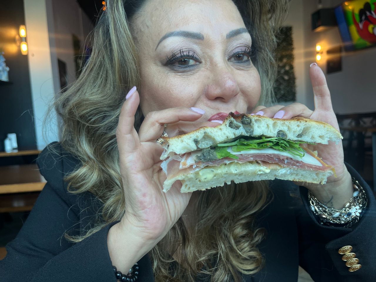 Patricia Toro bites into an Italian sandwich at Bevi Birra
