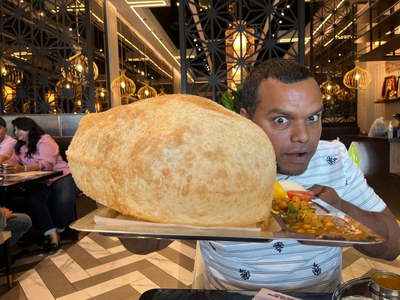 Chef Donnie Gomes holds a tray with a giant bhatura