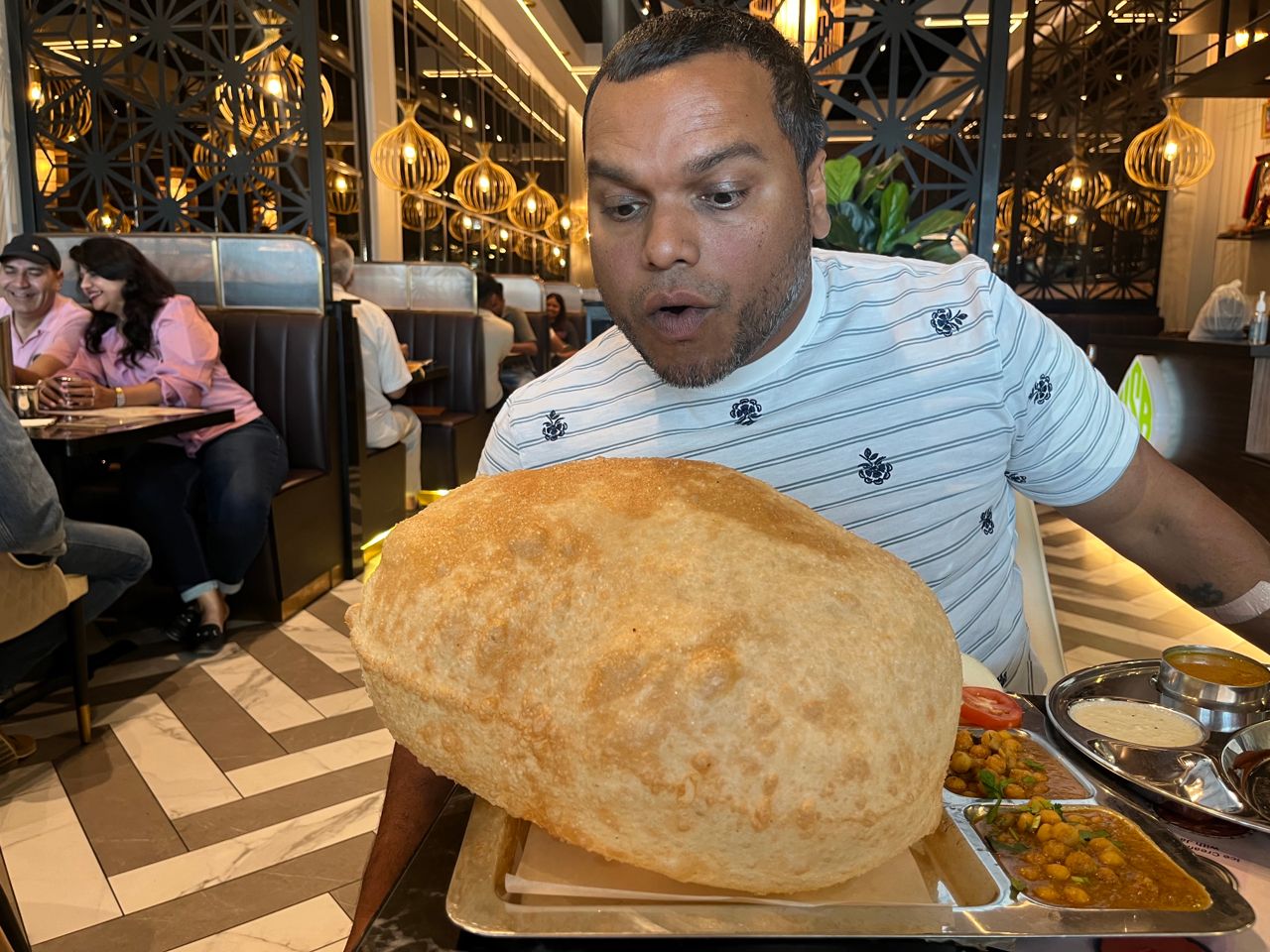 Chef Donnie Gomes looks at a tray holding a massive bhatura