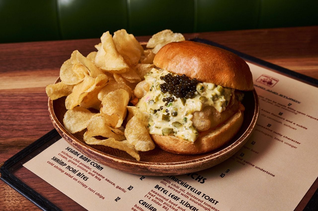 A cod sandwich topped with caviar and served with potato chips