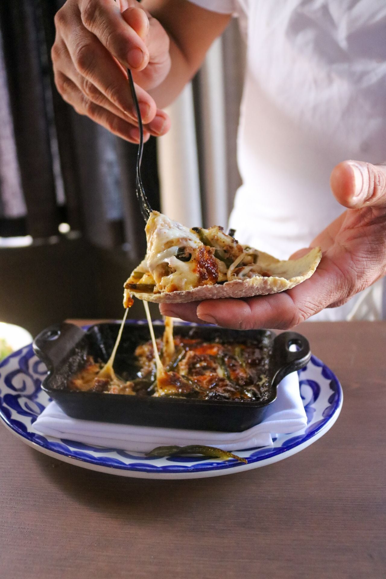 A chef puts queso onto a tortilla chip