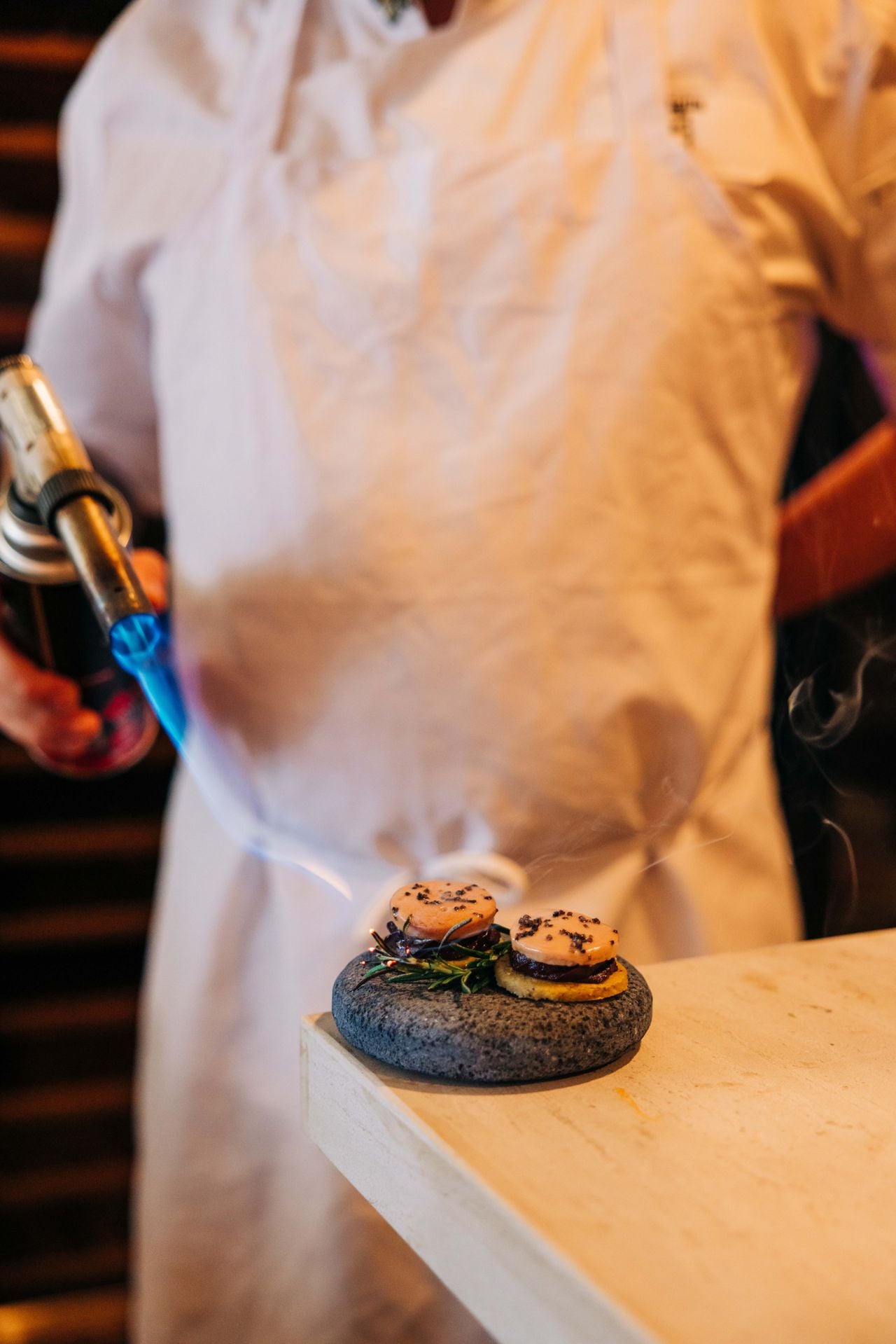 A chef torches gorditas topped with mole and Quebec foie gras