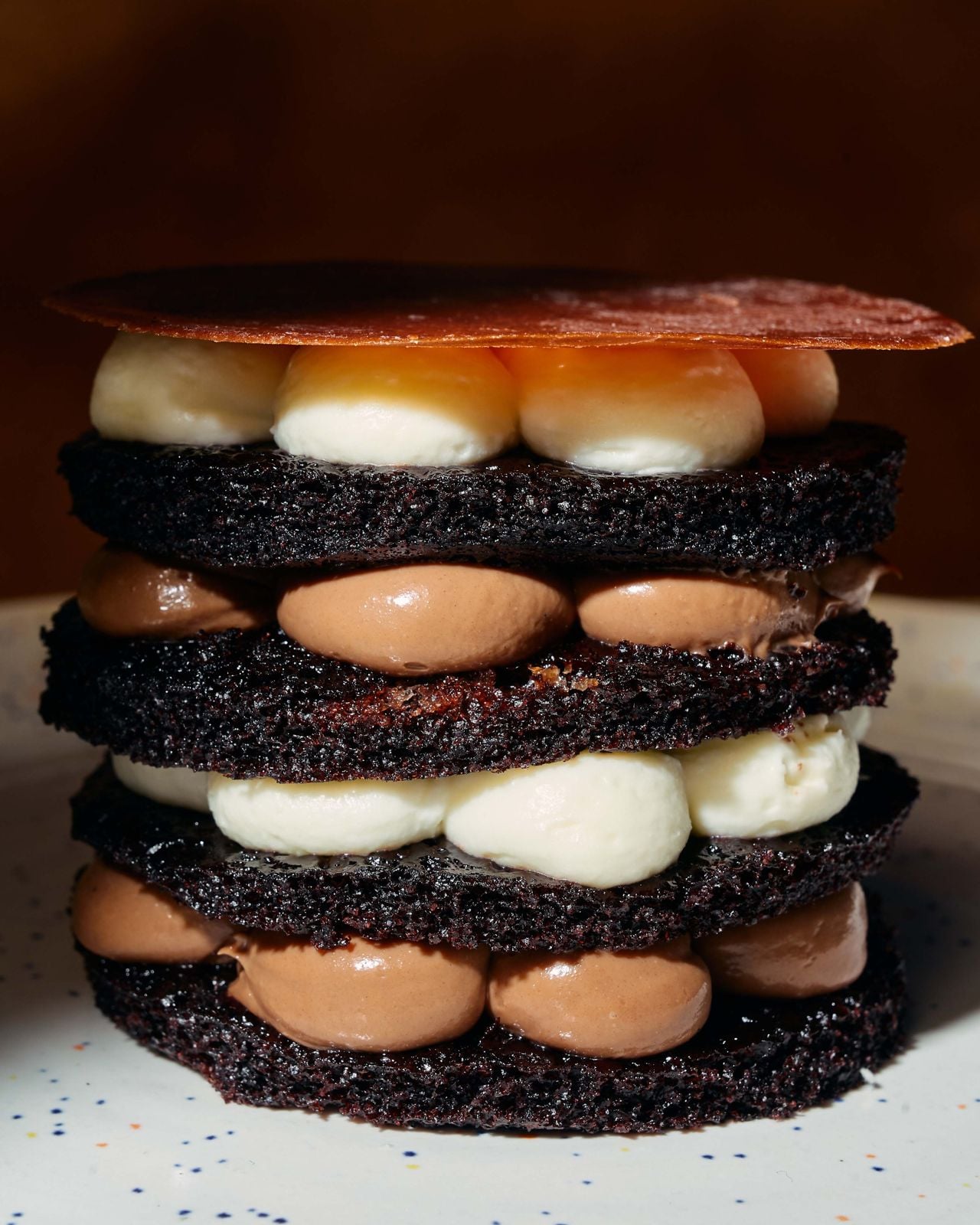 A sophisticated take on Filipino chocolate rice pudding, this dessert layers dense midnight chocolate cake with whipped white chocolate and toasted brown rice ganache, alternating with rich chocolate pastry cream