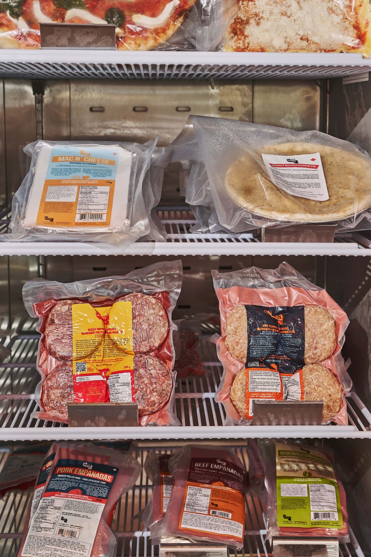 A fridge filled with vacuum-packed burger patties and side dishes at the Carbon Snack Bar