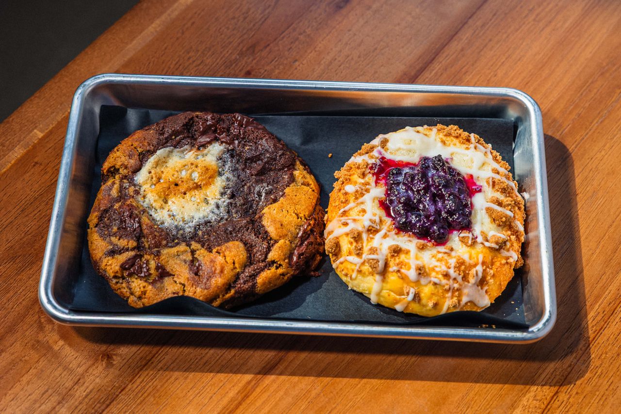 A tray with a s'mores cookie and a kolache topped with cream cheese icing and blueberry preserves
