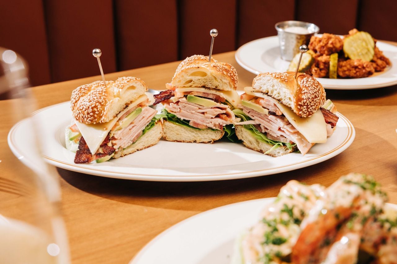 A brioche roll is stacked high with house-smoked turkey, thick-cut bacon, sharp aged cheddar and slices of juicy heirloom tomatoes, all slathered in a tangy honey-mustard mayo