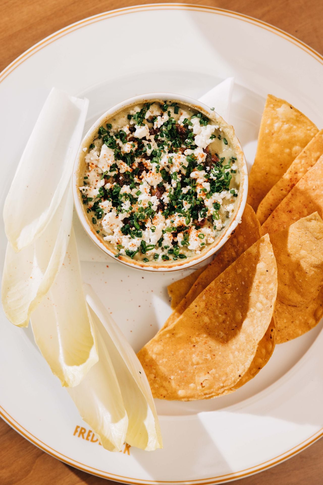 This dip is packed with loads of fresh spinach, artichokes and a blend of cheeses, bruléed to a golden crisp, topped with crumbled feta and minced chives, and served with tortilla chips and crunchy endive