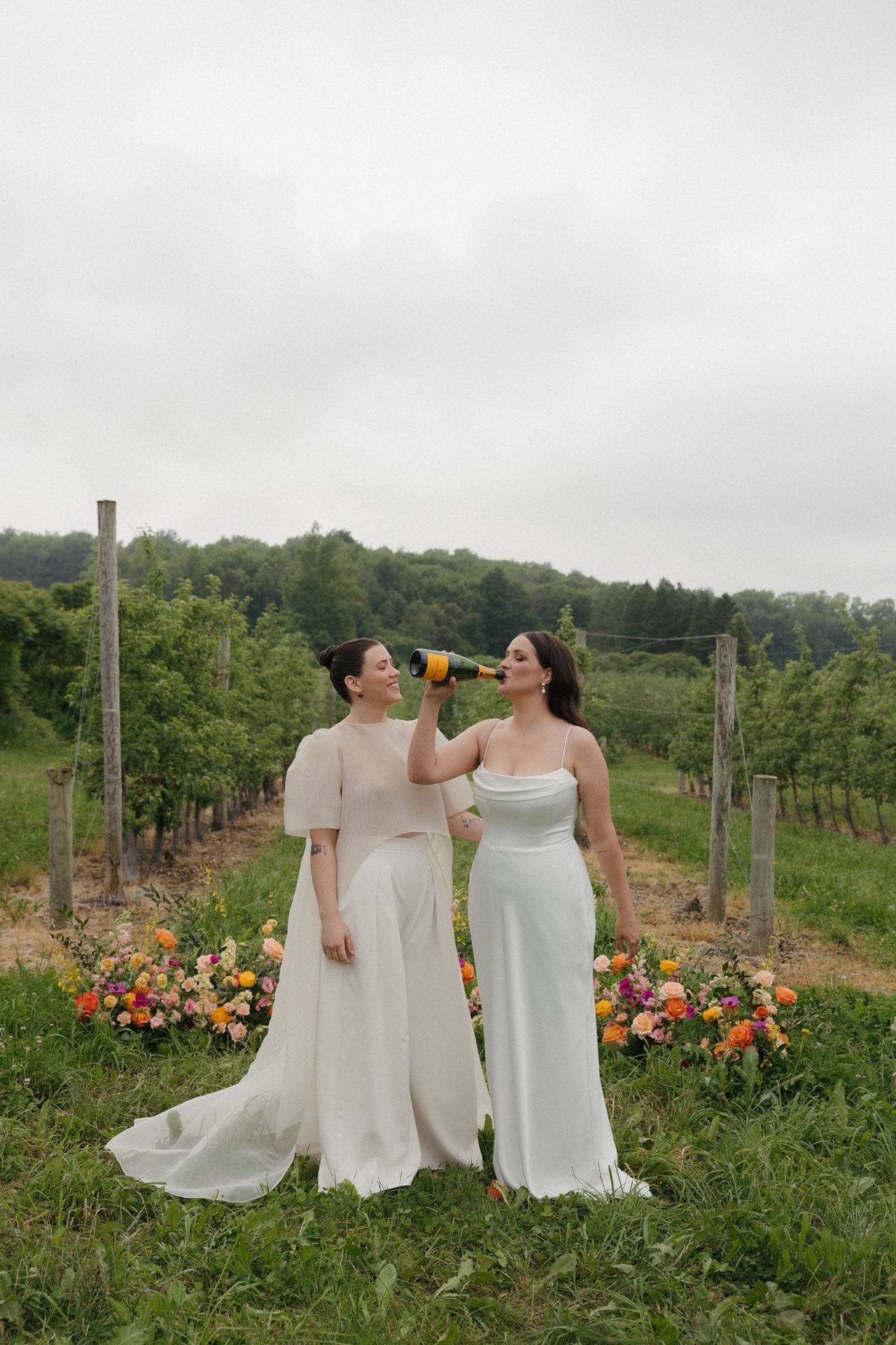 Two brides, one drinking champagne.