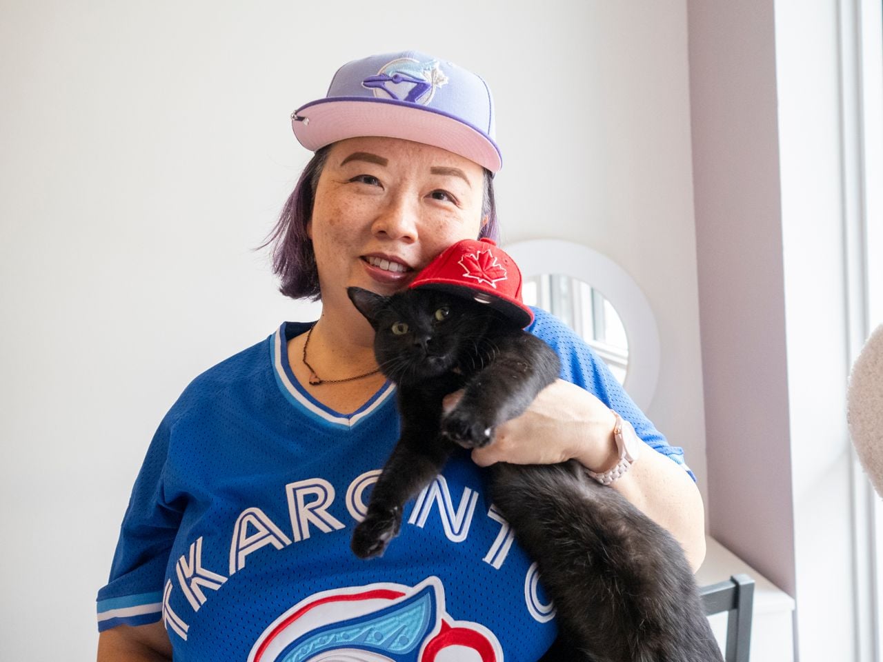 Woman with cat wearing Blue Jays hat