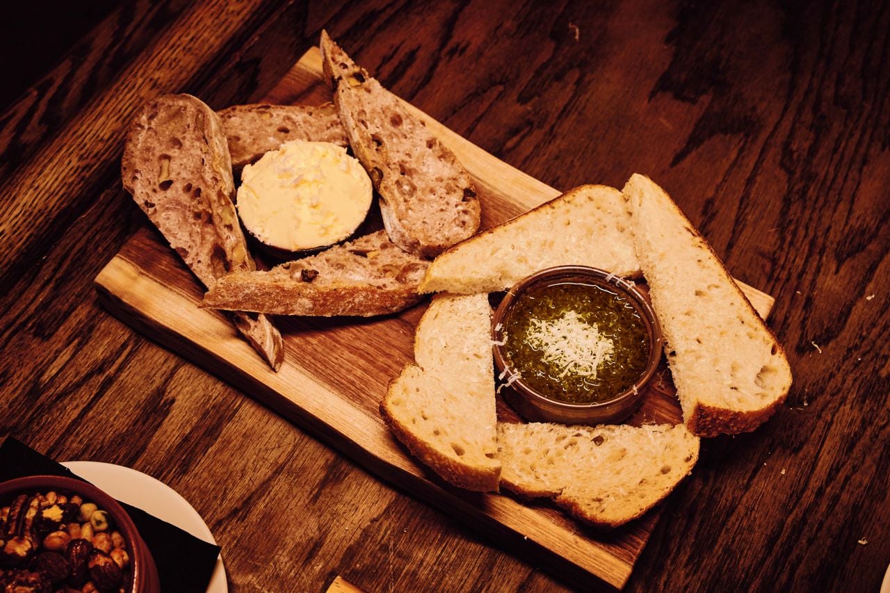 The bread board features thick slices of sourdough and raisin ciabatta served with whipped grass-fed PEI butter sprinkled with Maldon salt, and Tuscan olive oil infused with aged balsamic, Greek oregano and grated Parmigiano-Reggiano