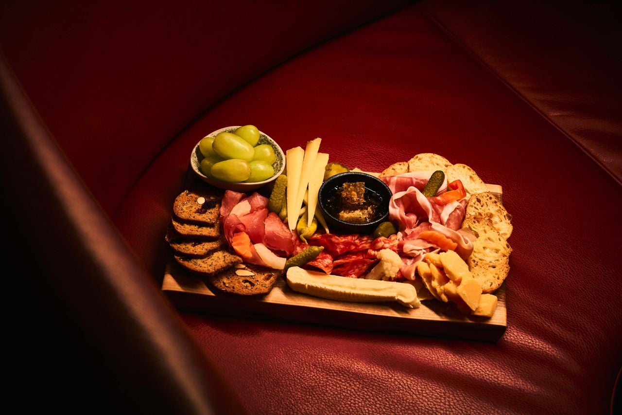 A mixed grazing board of meat, cheese, grapes, cornichons and crostini