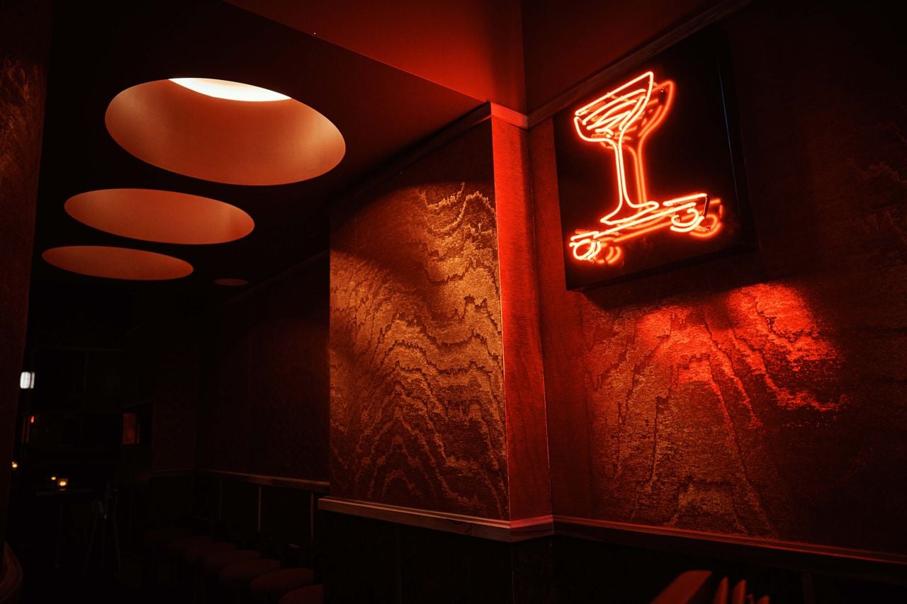 A neon sign in the shape of a martini glass hangs on the wall at Bar Cart