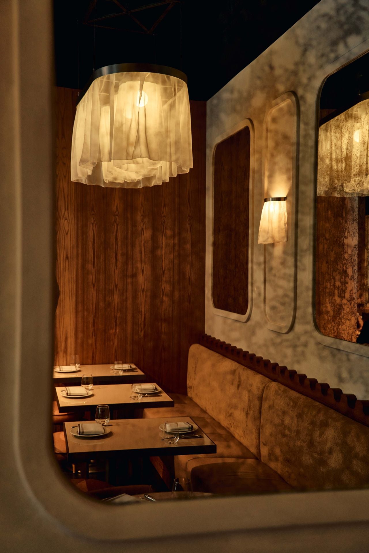 A mirror reflects a row of tables in the dining room of Eloise