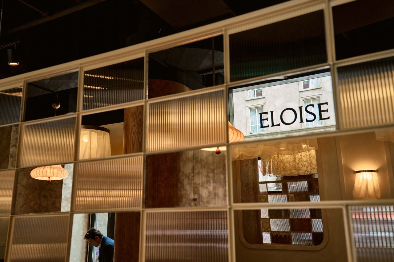 A wall of window reflects the sign at Eloise