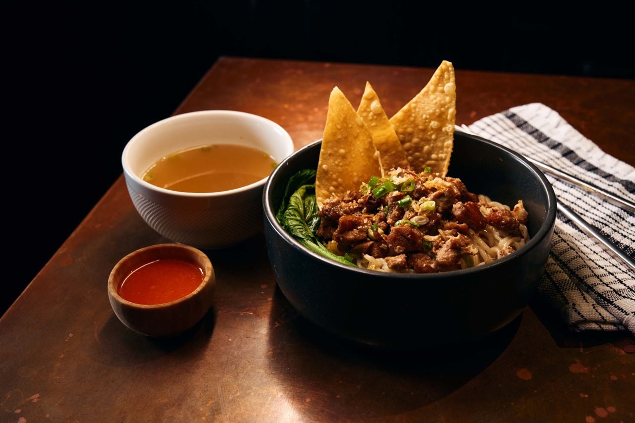 A bowl of bakmi ayam, served with fried wonton chips, blanched Chinese broccoli, bone broth and sambal