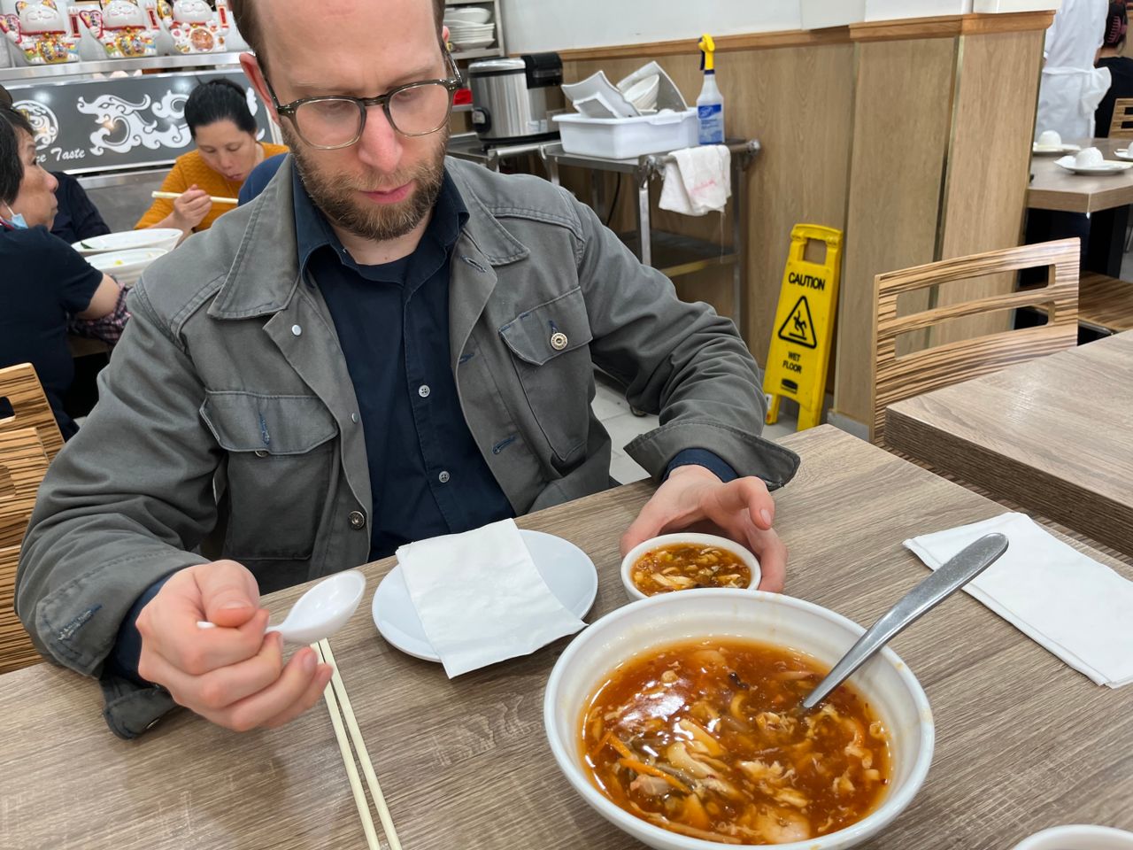 Chef Daniel Hyam sits at a table with hot and sour soup