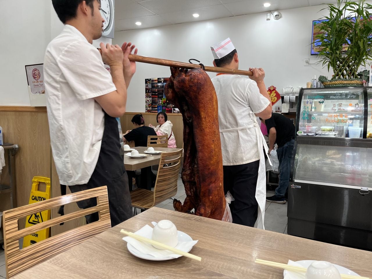 Two chefs carry a whole roasted pig