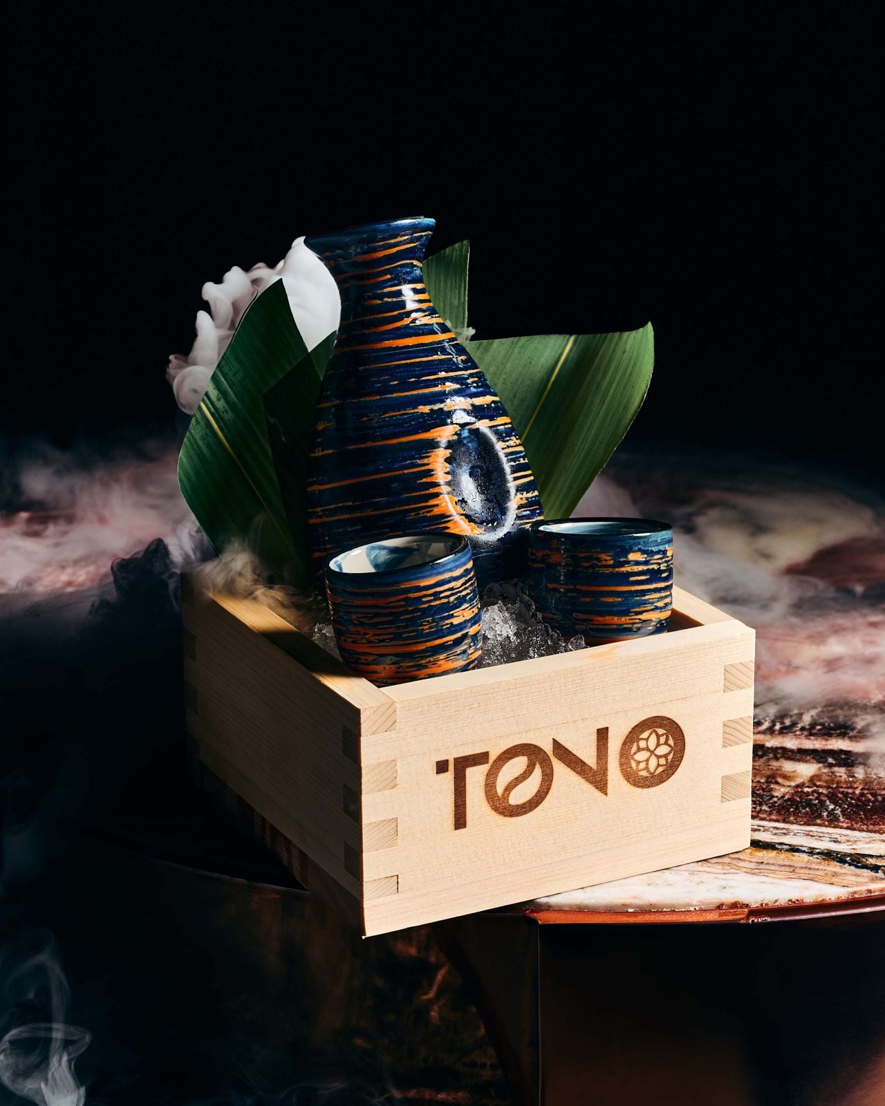 A box holds a bottle of sake and two cups