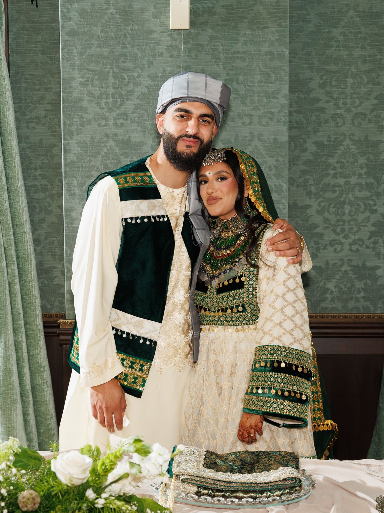 Gital and Harris embrace as they pose for a photo together, looking at the camera.
