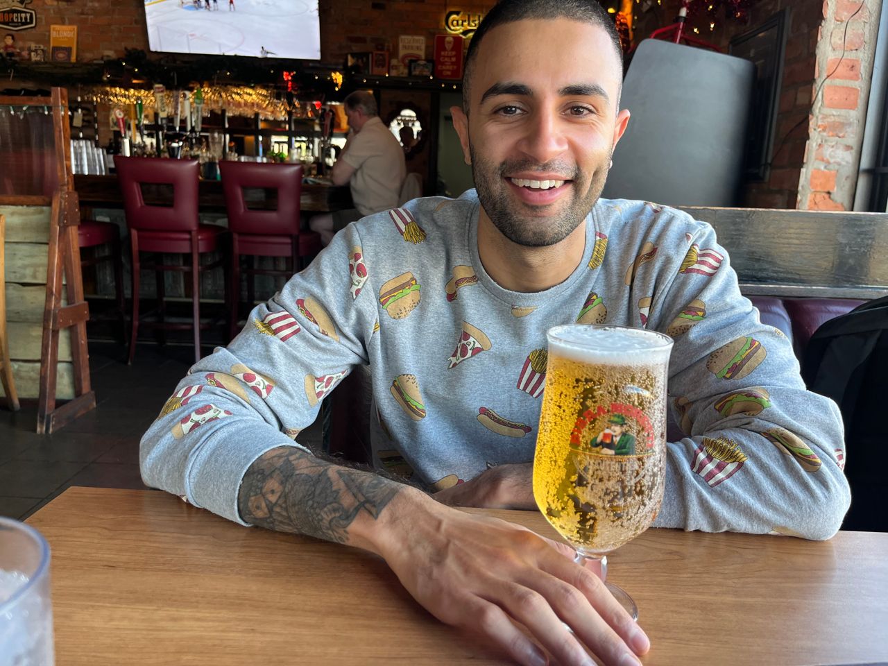 Chef Imrun Texeira sits at a table with a glass of beer