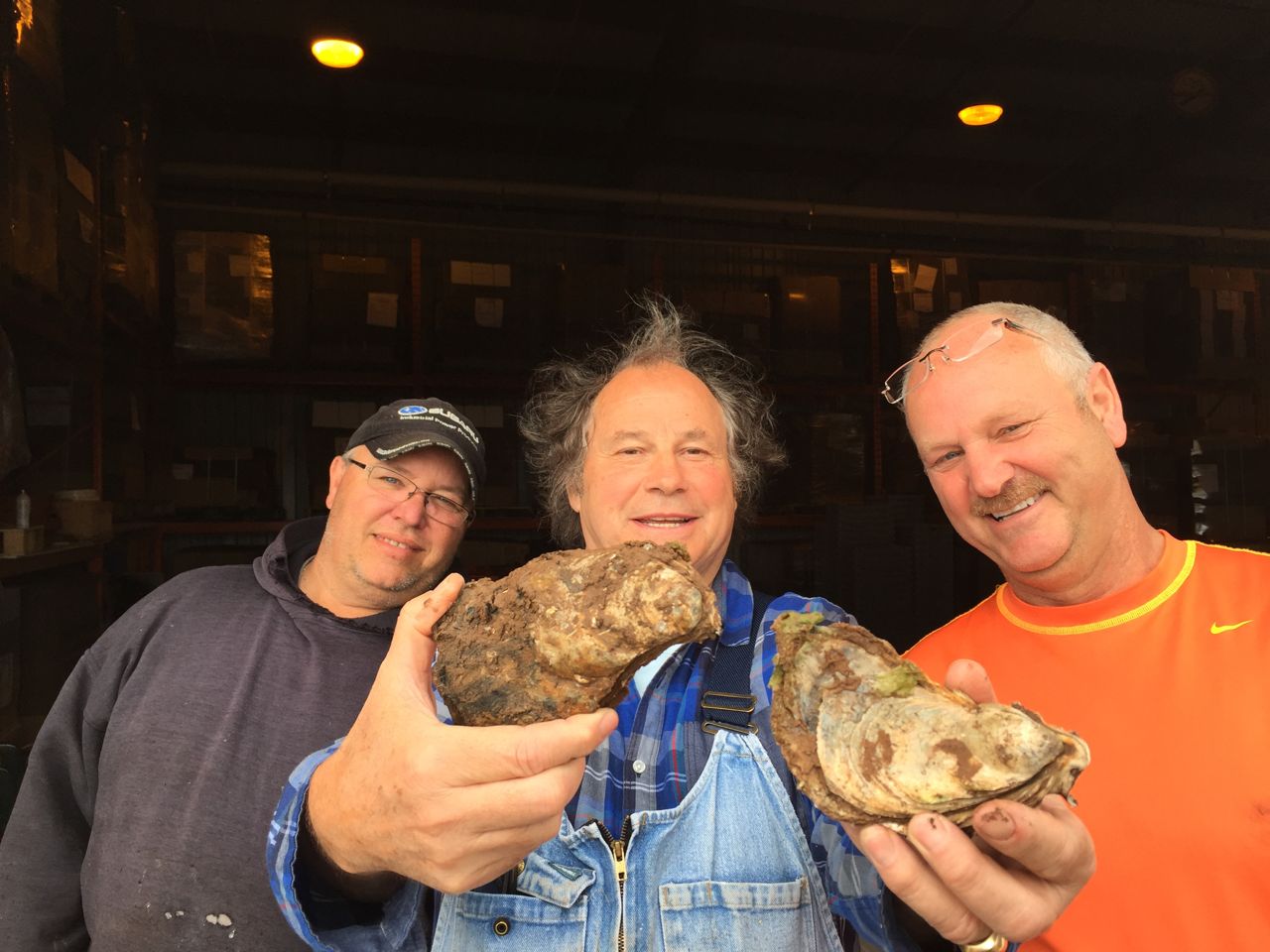 Rodney Clark holds two giant oysters out to the camera