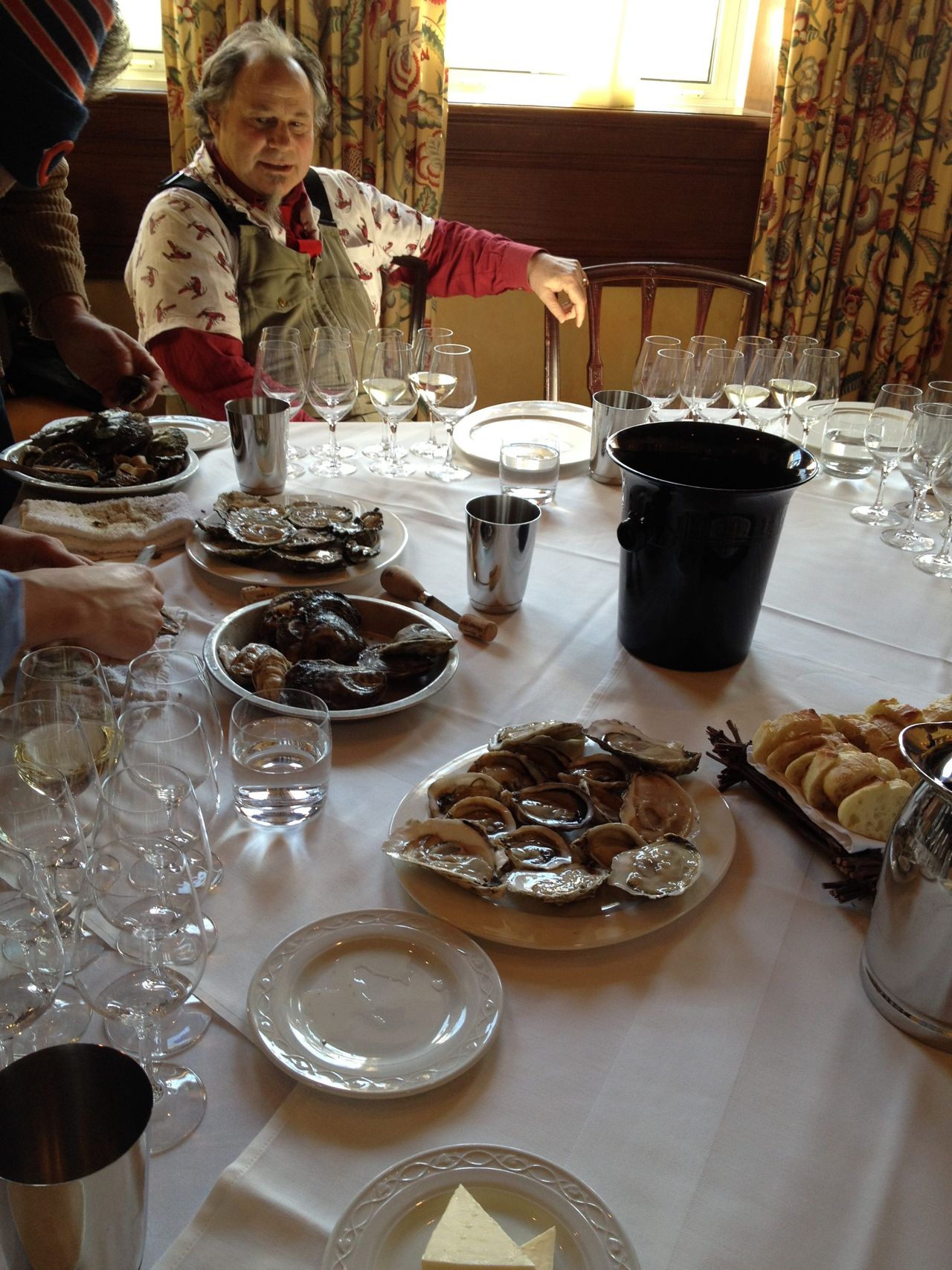 Rodney Clark sits at a table set with plates of oysters and glasses of wine