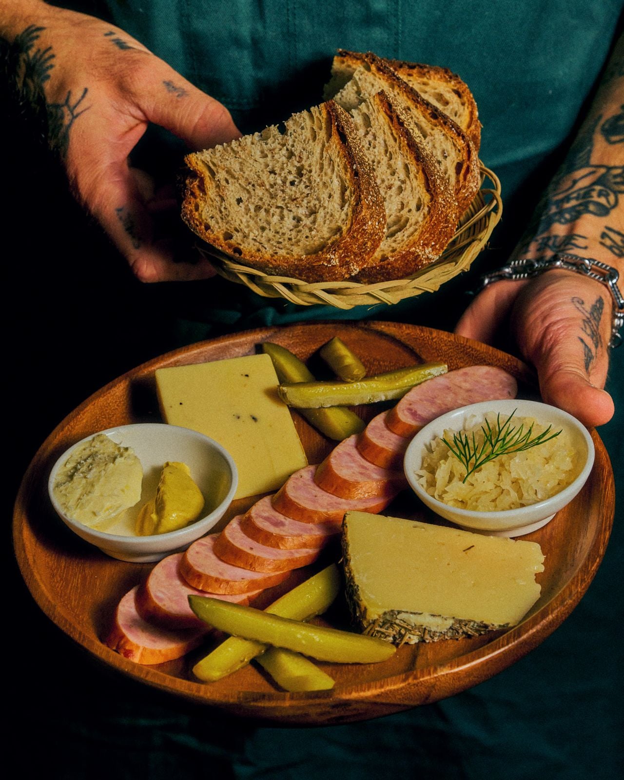 A plate of meat and cheese with a basket of bread at Sana