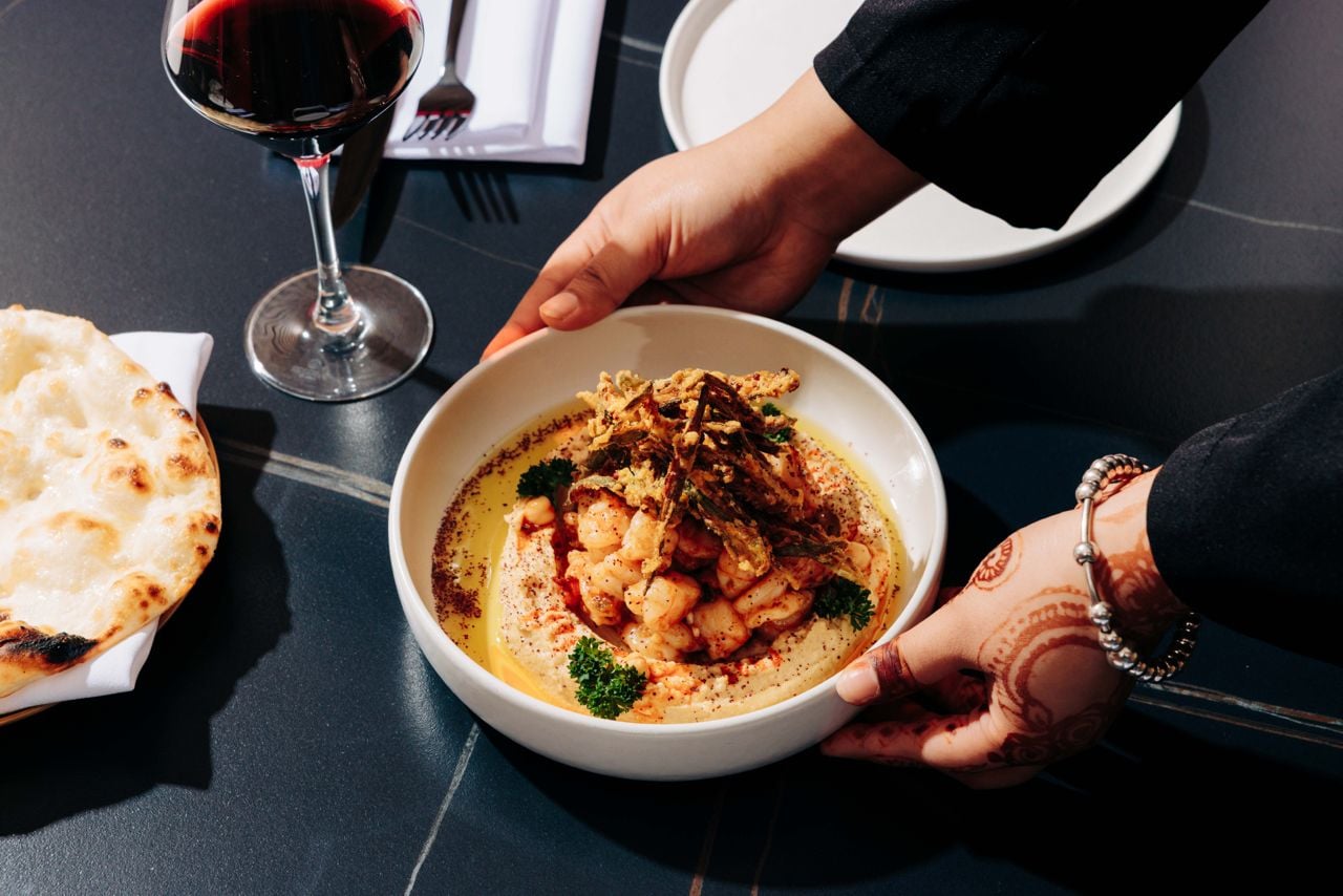 Hummus is crowned with tender grilled calamari and shrimp, then scattered with golden okra strings, whole chickpeas, a drizzle of chili-infused olive oil and a bright hit of sumac and fresh parsley