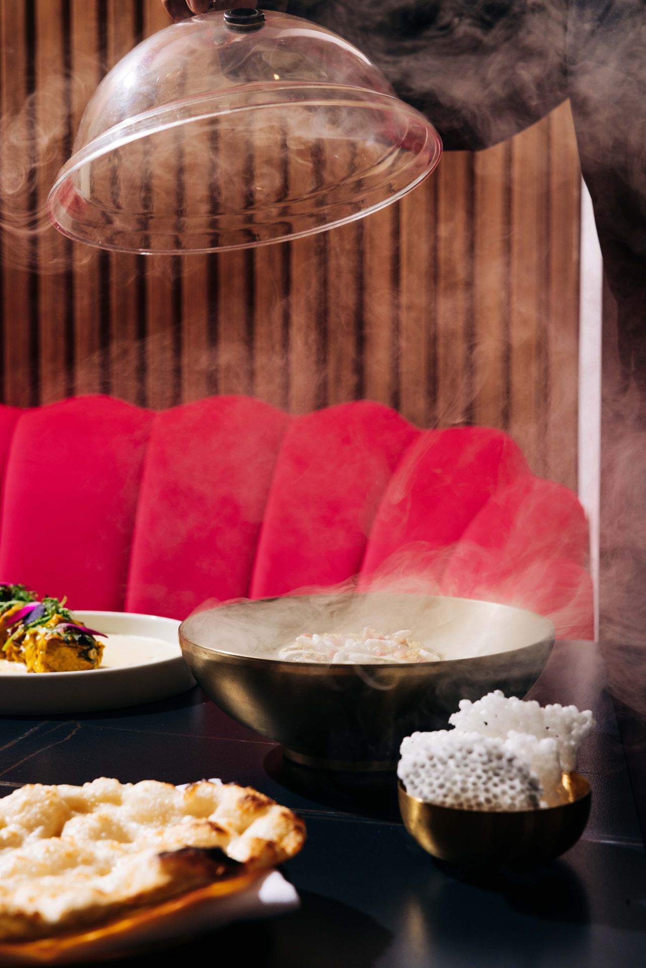 The smoked avocado tartare, done in the style of chaat, arrives beneath a glass cloche