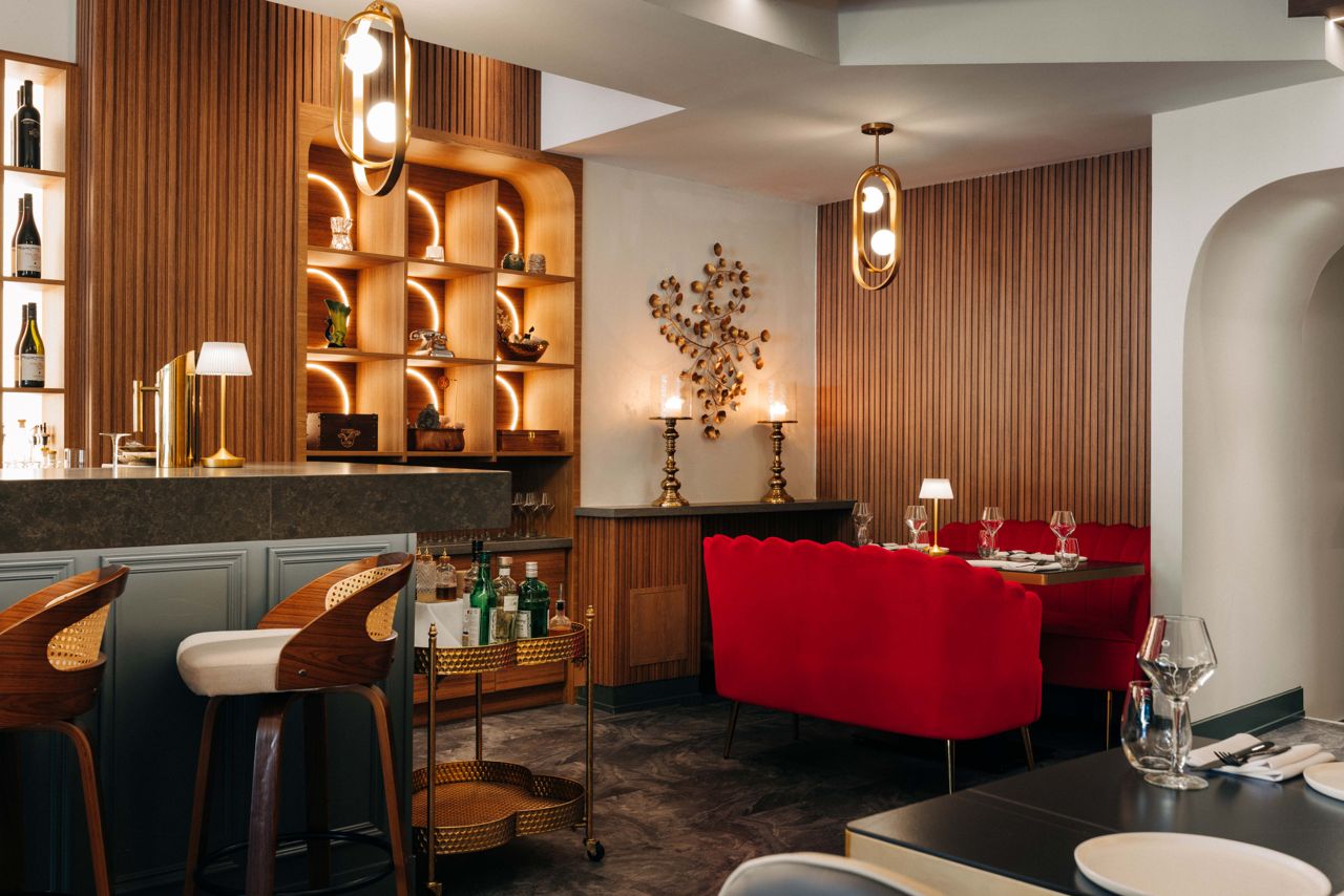 A back corner of ORO's dining room, featuring red velvet couch-style seating