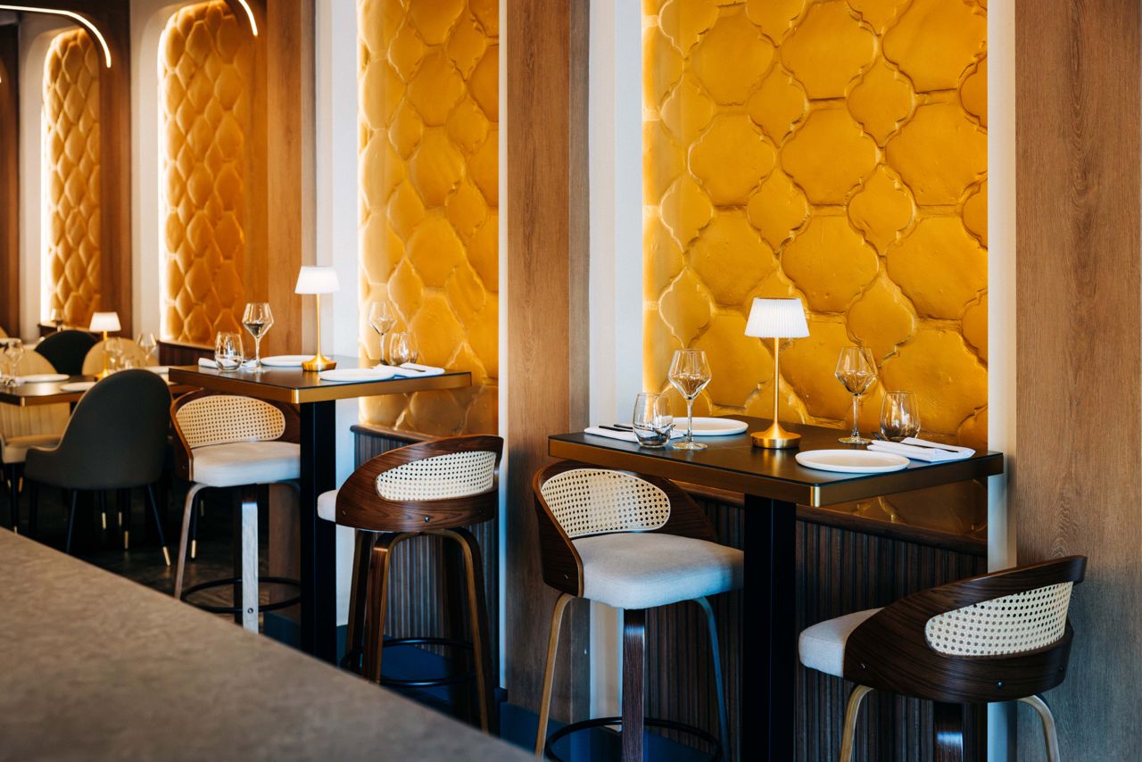 Two-top tables next to golden-hued walls in the dining room of ORO