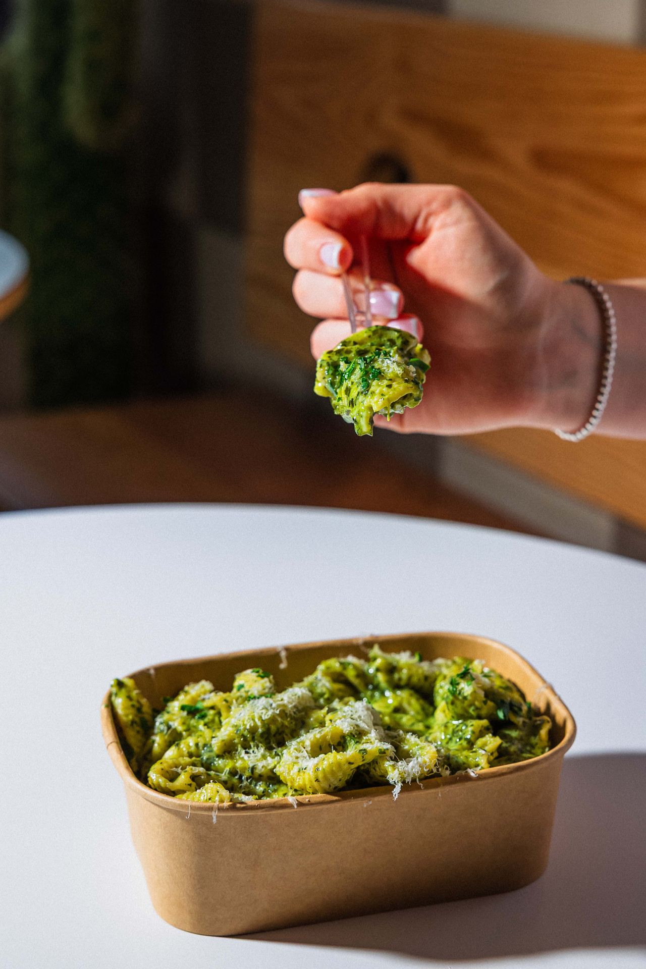 A person eats pasta in a pesto sauce using a fork