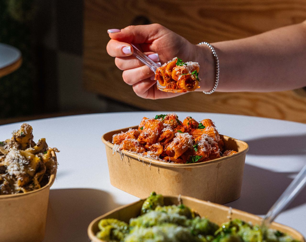 A person digs into rigatoni bolognese with a fork