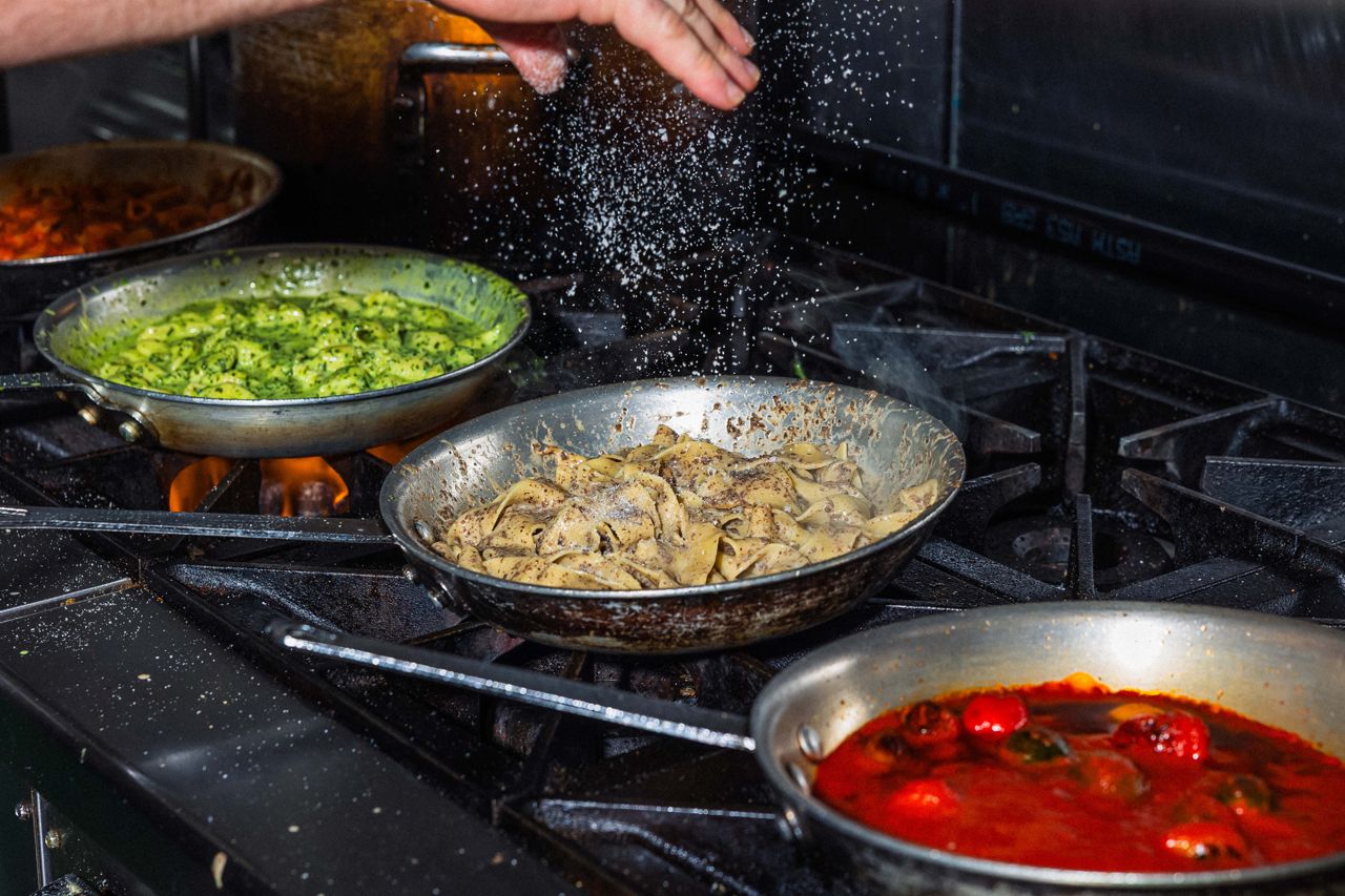 A chef adds salt to pasta